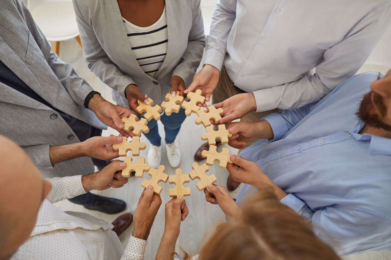 Team of Business People Connecting Pieces of Jigsaw Puzzle to Show Concept of Teamwork